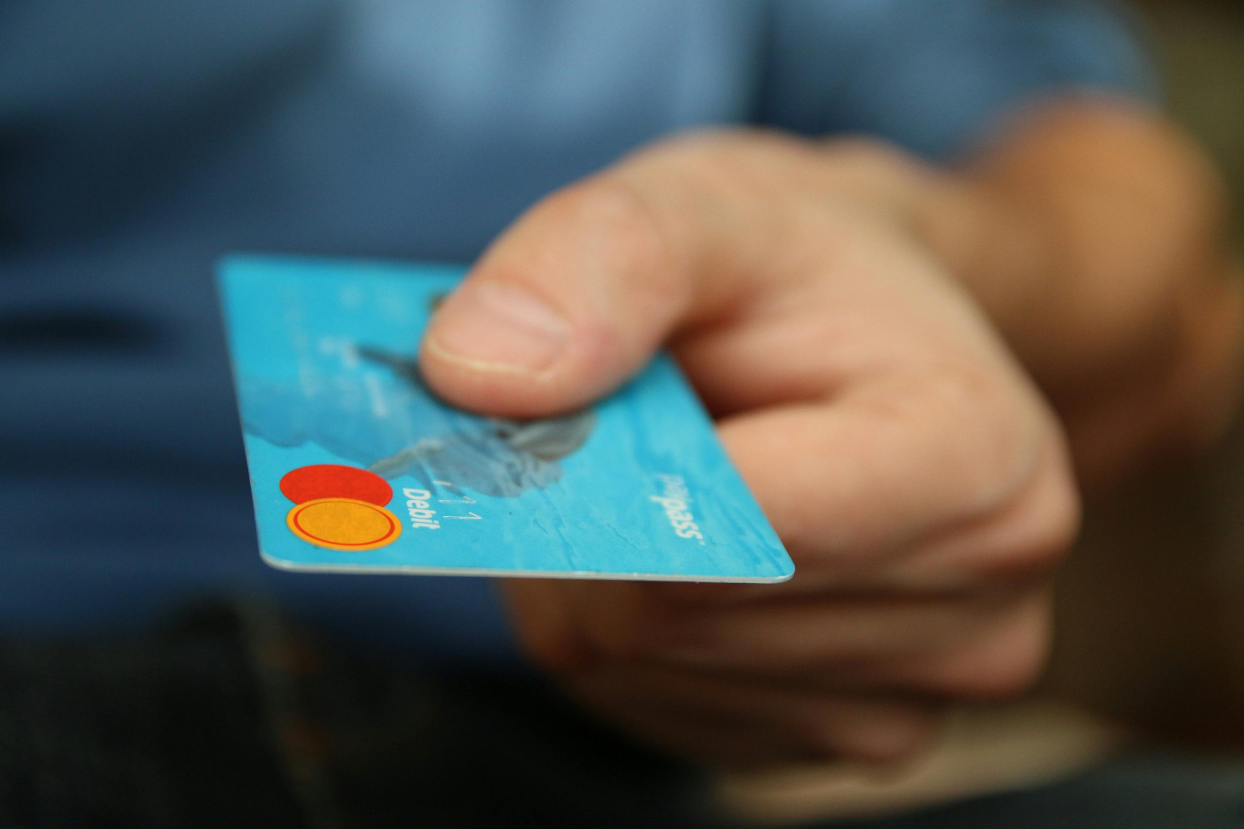 Someone handing over a mastercard. Photo by Pixabay on Pexels: https://www.pexels.com/photo/person-holding-debit-card-50987/